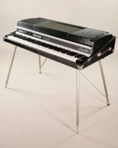 A vintage Rhodes Mark II Stage Piano with its iconic black body, silver panel, and chrome legs. This classic electric piano, widely used in jazz, funk, and rock music, features a full-sized keyboard and a sleek mid-century design.